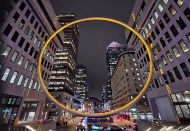 Andygibbphoto colour night image of The Ring, Place Ville Marie, Montreal in yellow colour with city street behind it
